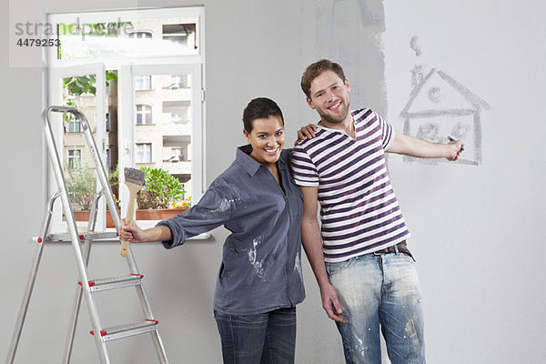 Ein junger Mann und eine junge Frau  die eine Wohnung renovieren.