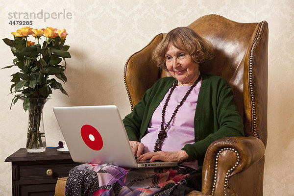 Eine ältere Frau entspannt sich mit einem Laptop