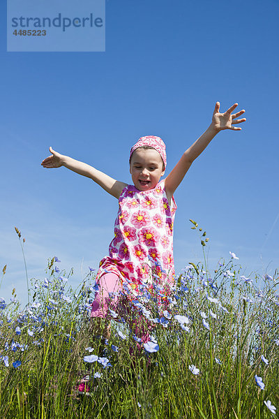 Mädchen läuft über eine Blumenwiese
