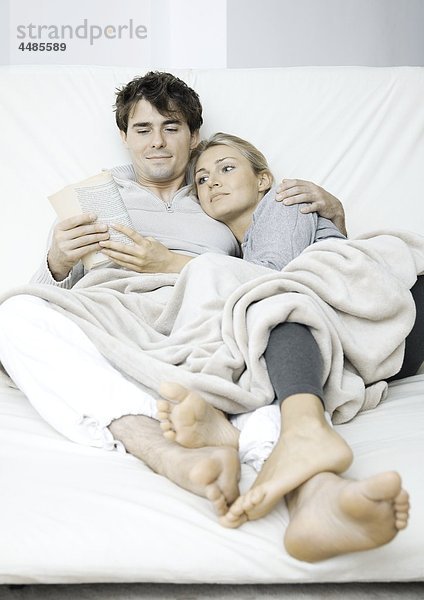 Junges Paar im Bett liest ein Buch