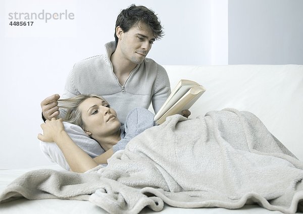 Junges Paar auf dem Bett liest ein Buch