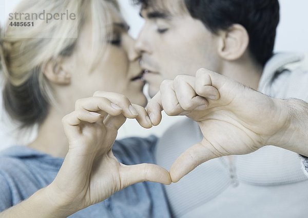 Verliebtes junges Paar formt ein Herz mit ihren Händen