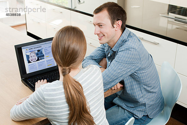 Junges Paar sucht Versicherung auf dem Laptop