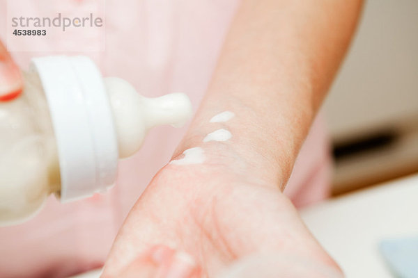 Mutter testet Babymilch am Handgelenk