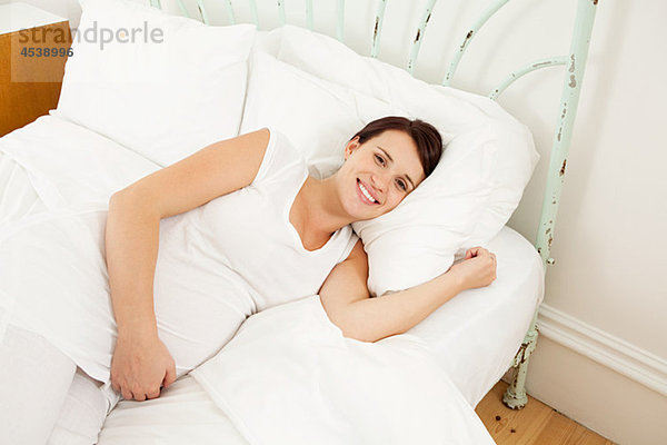 Schwangere Frau im Bett liegend