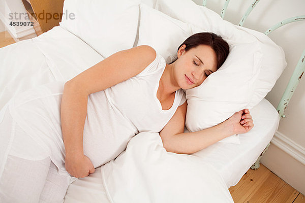 Eine schwangere Frau schläft im Bett.