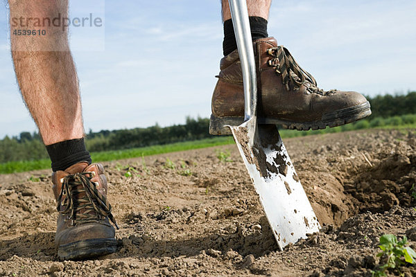 Bauer beim Graben auf dem Feld