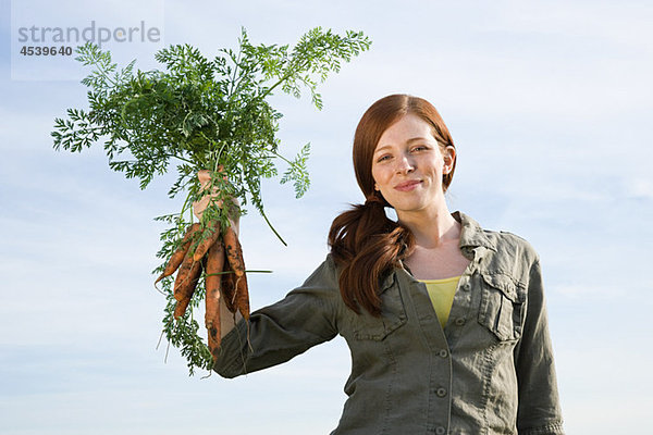 Junge Frau mit frisch gepflückten Karotten