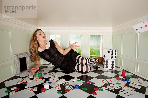 Junge Frau in kleinem Raum wirft Spielkarte