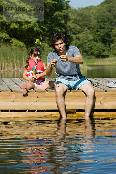 Vater und Tochter fischen vom Steg aus