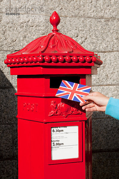 Person  die Postkarte in den Briefkasten legt  London