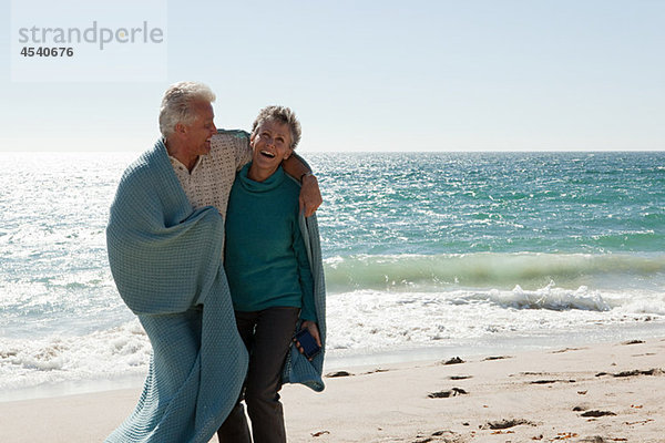 Erwachsenes Paar am Strand in Decke gehüllt