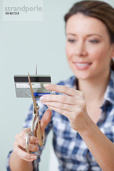 Junge Frau schneidet Kreditkarte