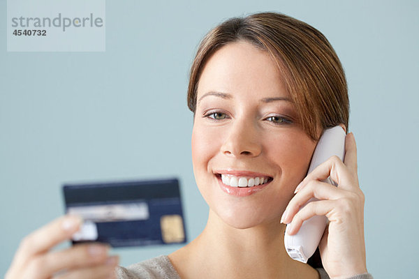Junge Frau am Telefon mit Kreditkarte