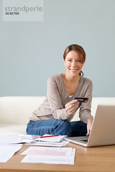 Junge Frau mit Kreditkarte mit Laptop