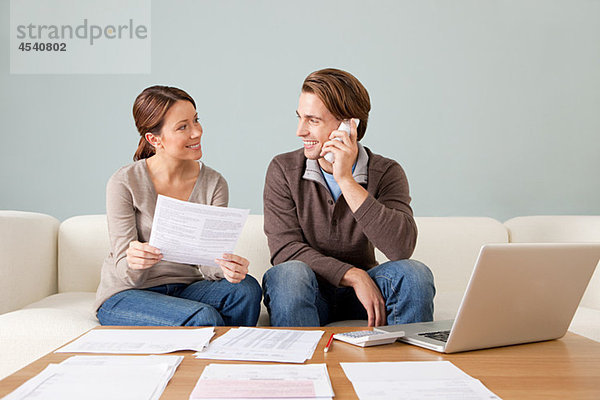 Junges Paar mit Computer und Papierkram