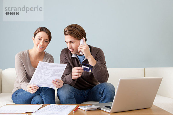 Junges Paar mit Computer und Papierkram