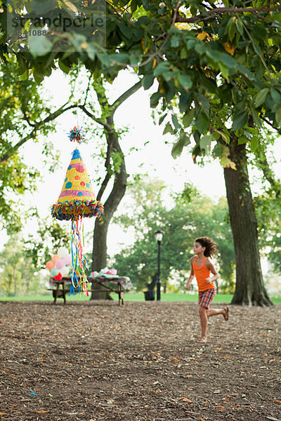 Mädchen bei der Geburtstagsfeier an Pinata vorbeilaufend