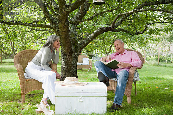 Mature couple outdoors  man reading book