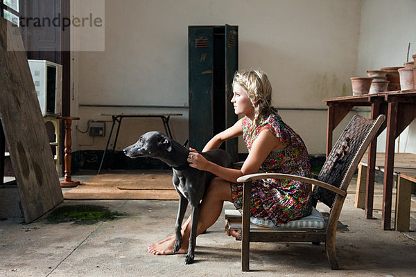 Junge Frau sitzt auf Stuhl mit Hund