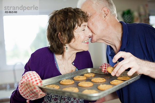 Seniorenpaar beim Küssen mit selbstgebackenen Keksen