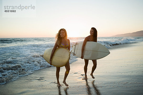 Surferinnen am Meer bei Sonnenuntergang