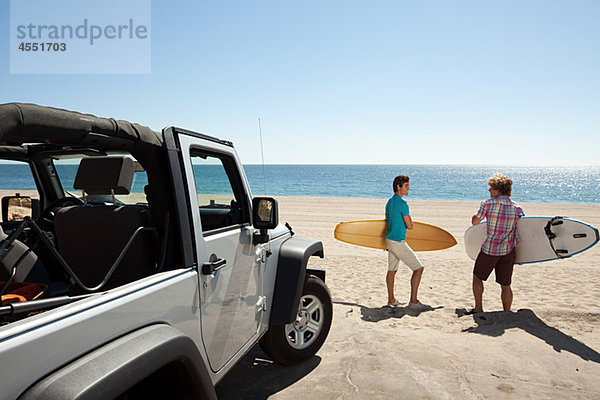 Zwei junge Männer am Strand mit Surfbrettern