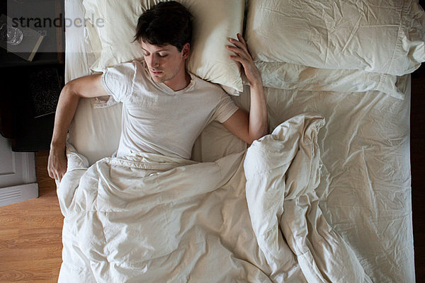 Mann schläft allein im Doppelbett
