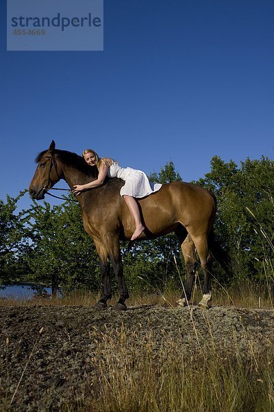 Frau liegend auf Pferd