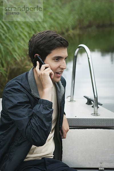 Junger Mann auf Boot sprechen auf Handy