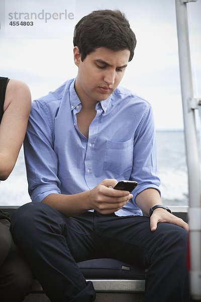 Junger Mann auf Boot Text-messaging