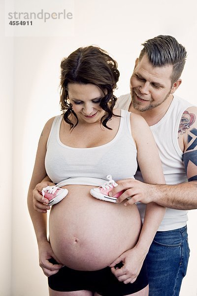 Mann  Booties auf schwangere Frauen Bauch  lächelnd