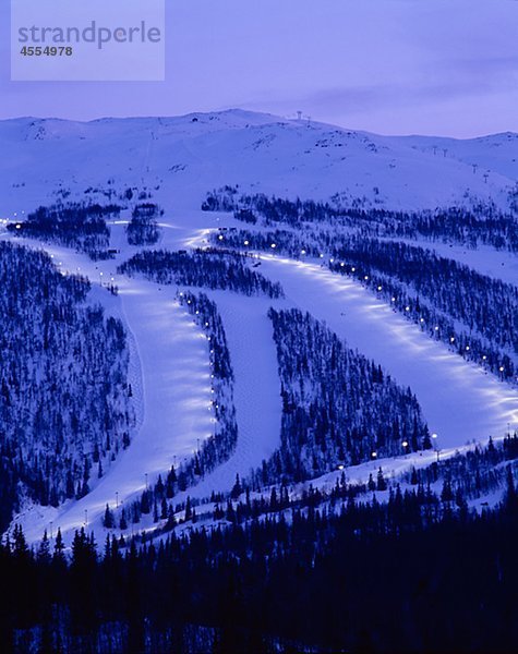 Schneebedeckte Berge und Skipiste in der Dämmerung