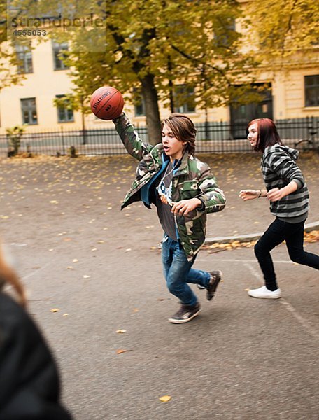 Teenager spielen Basketball in Schulhof