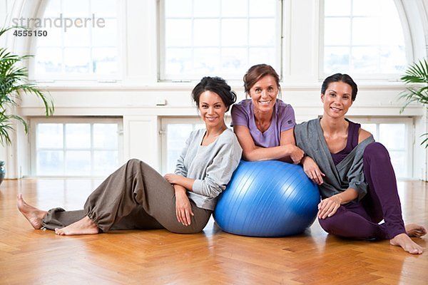 Portrait von drei Frauen mit Fitness-Ball im Fitness-Studio