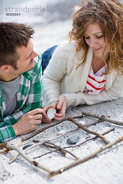 Mitte adult paar spielen Tic Tac Toe am Strand