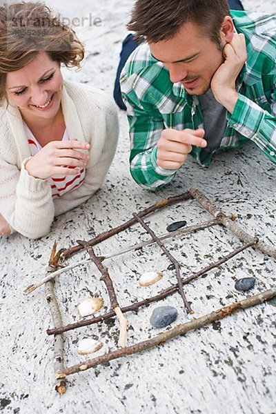 Mitte adult paar spielen Tic Tac Toe am Strand