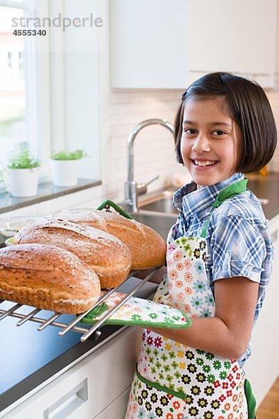 Mädchen hält Metallrost mit hot Brot loafs