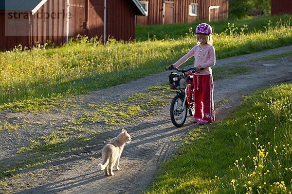 Mädchen mit Fahrrad in der Nähe von Cat im Dorf