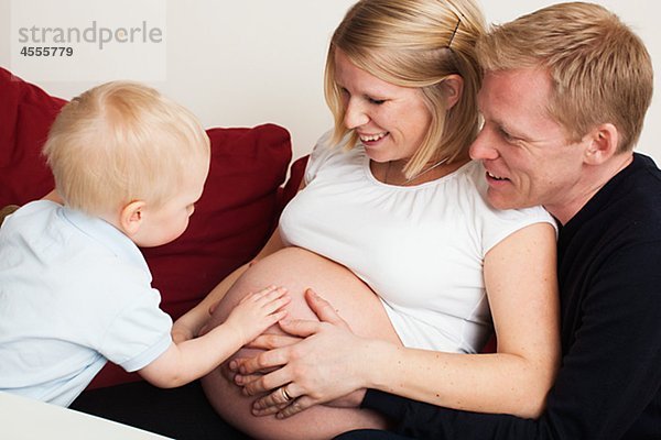 Familie berühren schwangere Mütter Magen auf sofa