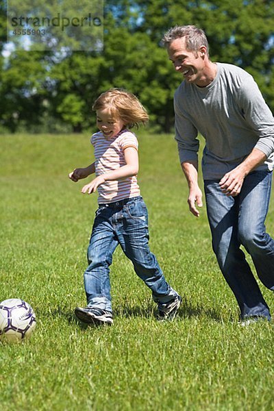 Vater und Sohn spielen Fußball in hellem Sonnenlicht