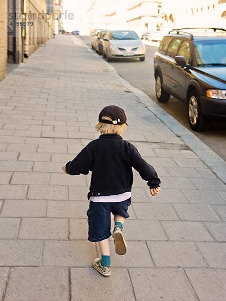 Rückansicht des Boy läuft Bürgersteig