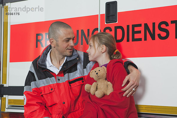 Krankenwagenmann  der sich um das Mädchen im Bus kümmert.