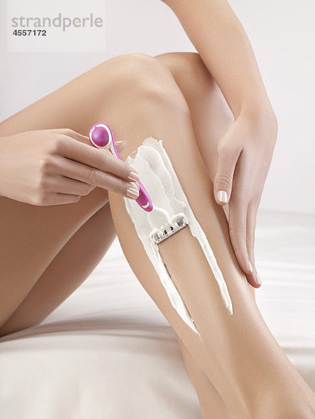 Frau rasiert sich das Bein
