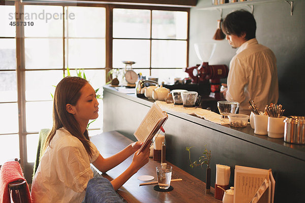 Japanische Frau lesen ein Buch in einem Café