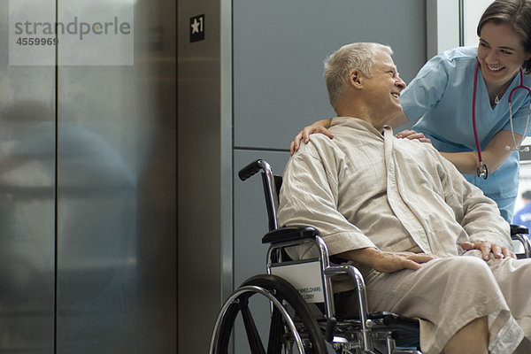 Krankenschwester hilft Patientin im Rollstuhl
