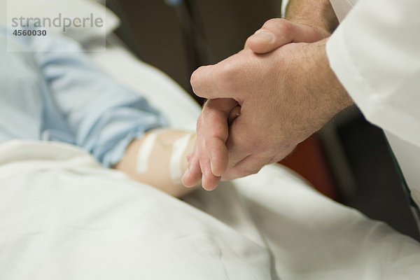 Arzt hält Patientenhand  abgeschnitten