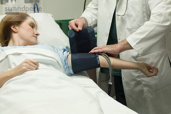 Arzt beim Anlegen der Blutdruckmanschette an den Patienten im Krankenhaus