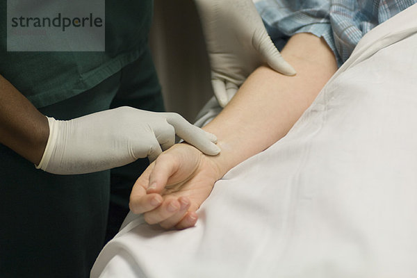 Krankenschwester überprüft den Puls des Patienten