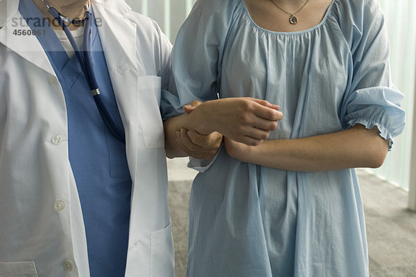 Patient hält sich zur Unterstützung am Arm der Krankenschwester fest.